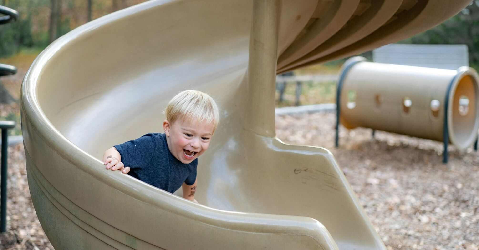 Young child smiling while sliding down a playground slide