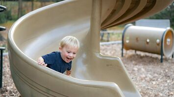 Young child smiling while sliding down a playground slide