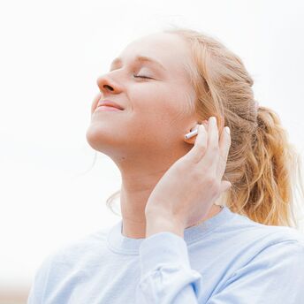 Person wearing wireless earbud and listening