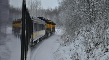 Train travelling through snowy countryside during winter weather
