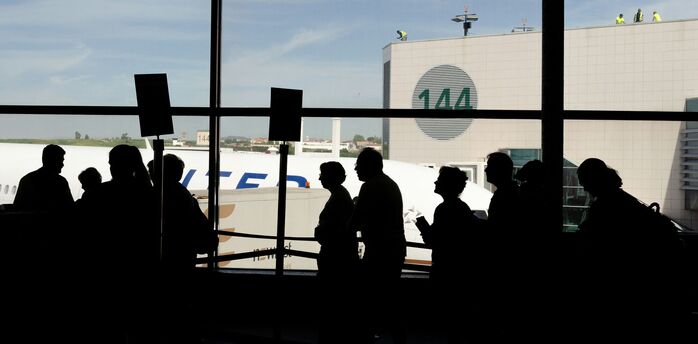 Passengers queue inside an airport terminal