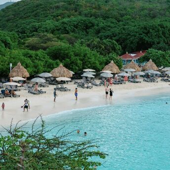 Beach with sun loungers, umbrellas and people swimming