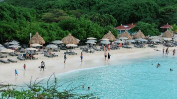 Beach with sun loungers, umbrellas and people swimming