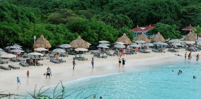 Beach with sun loungers, umbrellas and people swimming