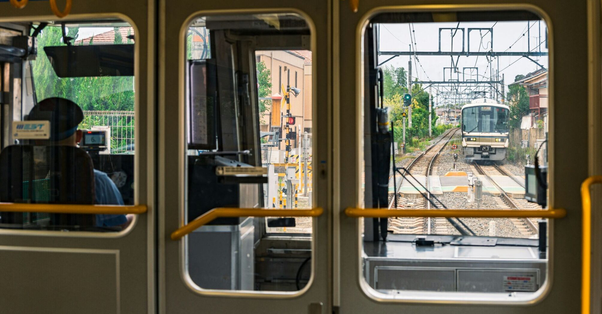 Train approaching on suburban rail line viewed from inside carriage
