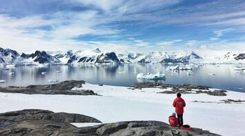 Two visitors overlooking a snowy Antarctic bay