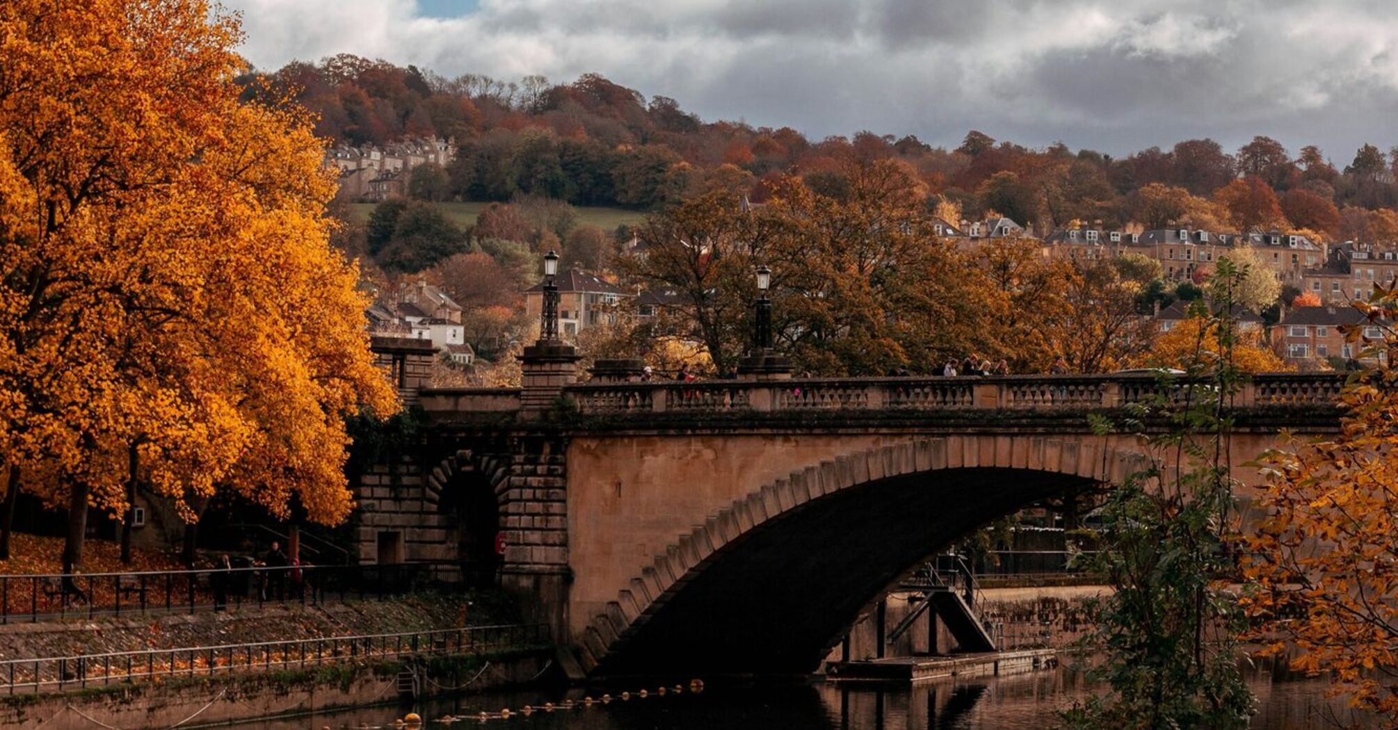 Stone arch bridge over a river surrounded by autumn trees