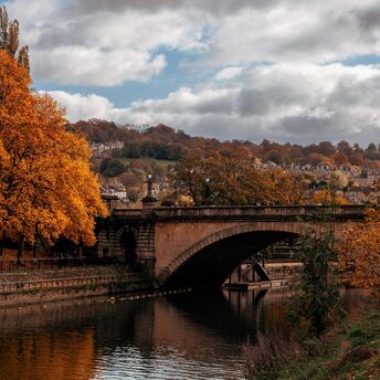 Stone arch bridge over a river surrounded by autumn trees