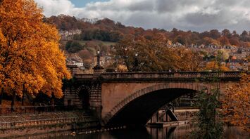 Stone arch bridge over a river surrounded by autumn trees
