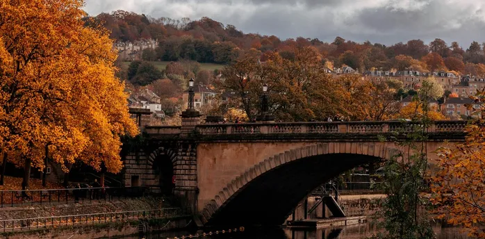 Stone arch bridge over a river surrounded by autumn trees