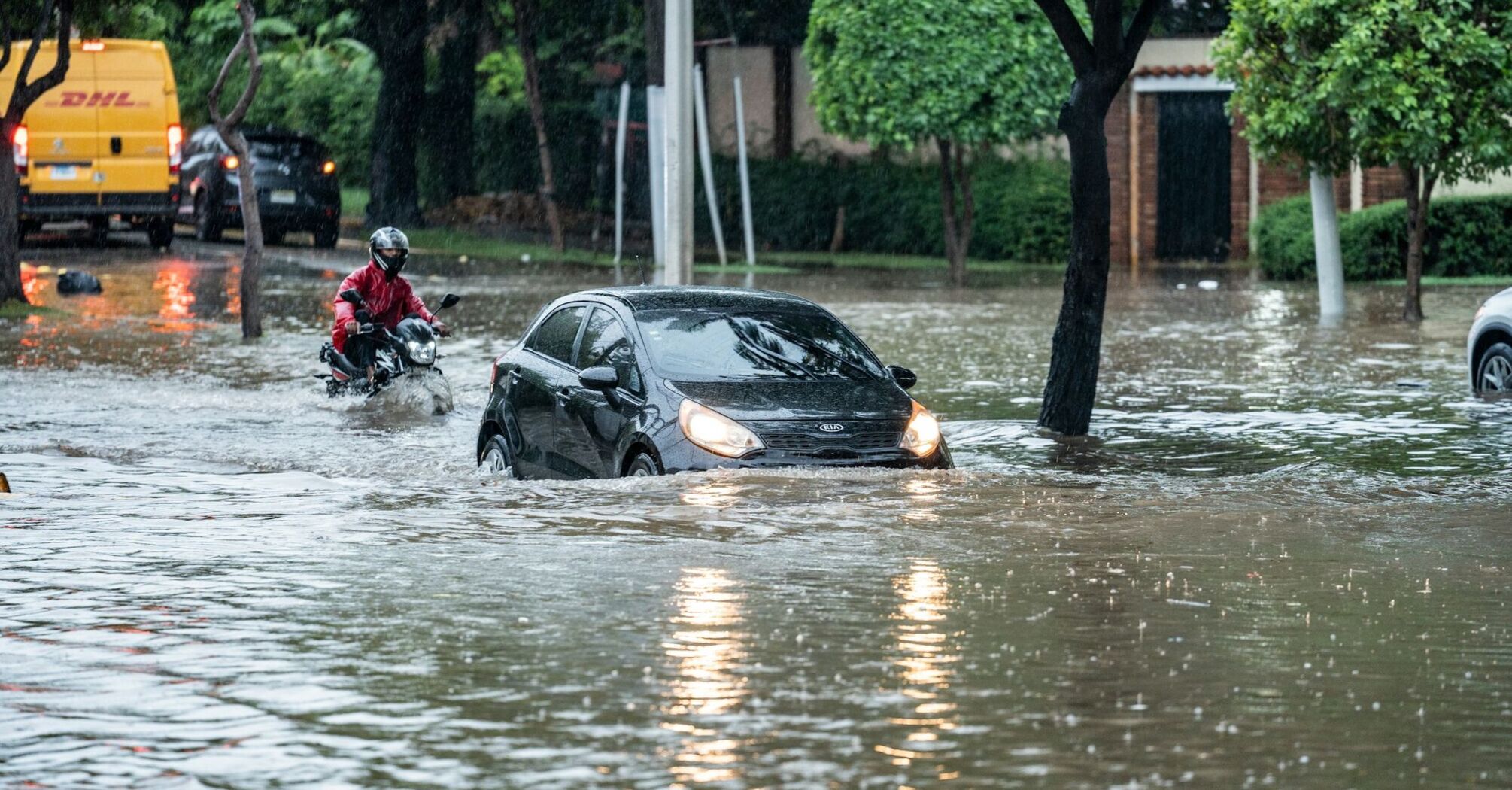 Car and motorcyclist navigating a flooded street