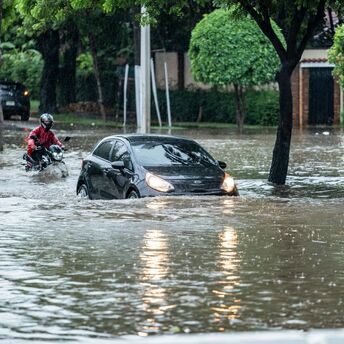 Car and motorcyclist navigating a flooded street