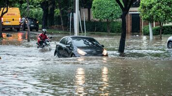 Car and motorcyclist navigating a flooded street