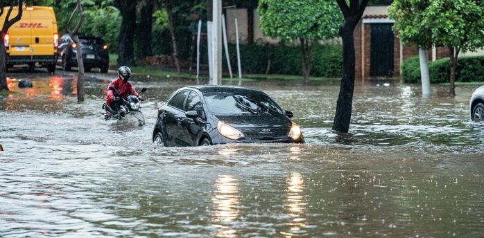 Car and motorcyclist navigating a flooded street