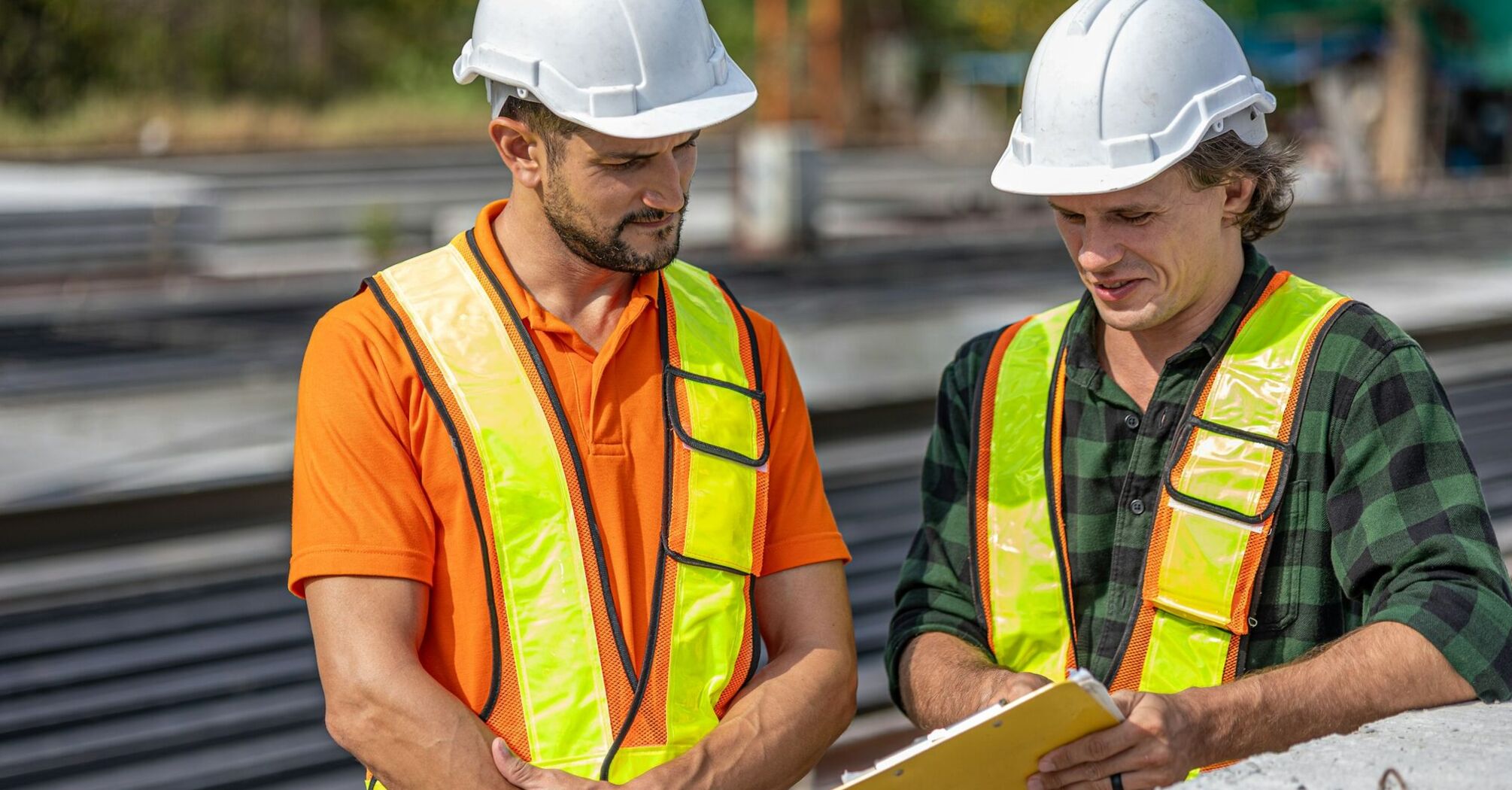 Two railway workers reviewing documents beside tracks