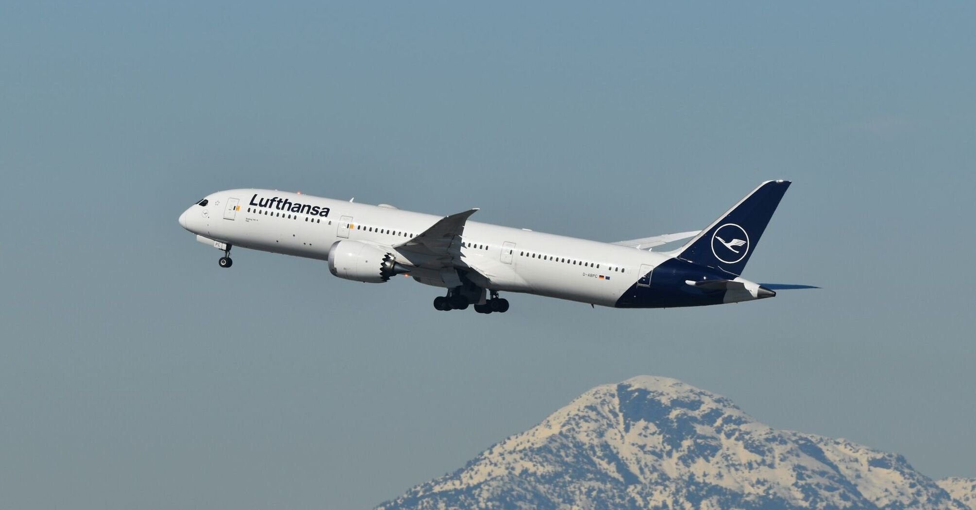 Lufthansa passenger jet flying above a snow-covered mountain