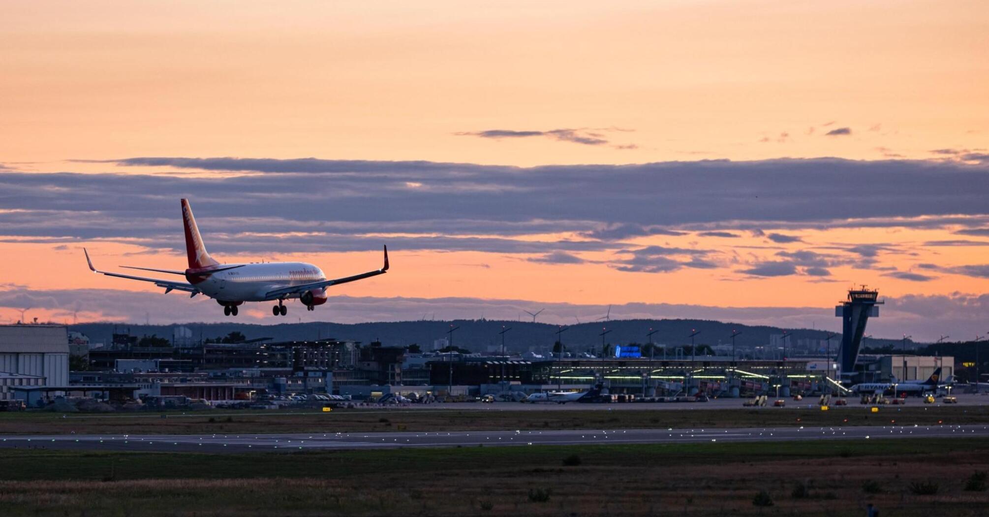Passenger aircraft approaching an airport runway at sunset