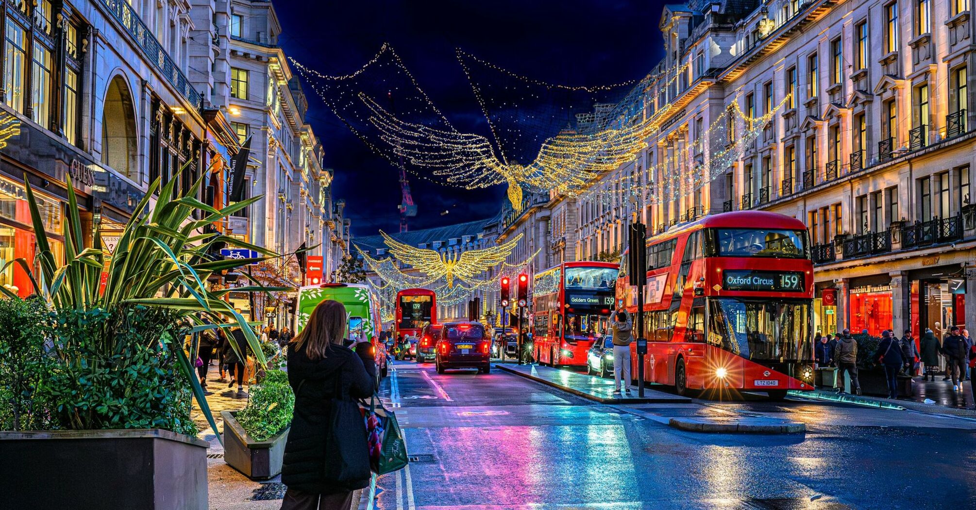 Red double-decker buses beneath Christmas angel lights on London's Regent Street