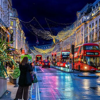 Red double-decker buses beneath Christmas angel lights on London's Regent Street