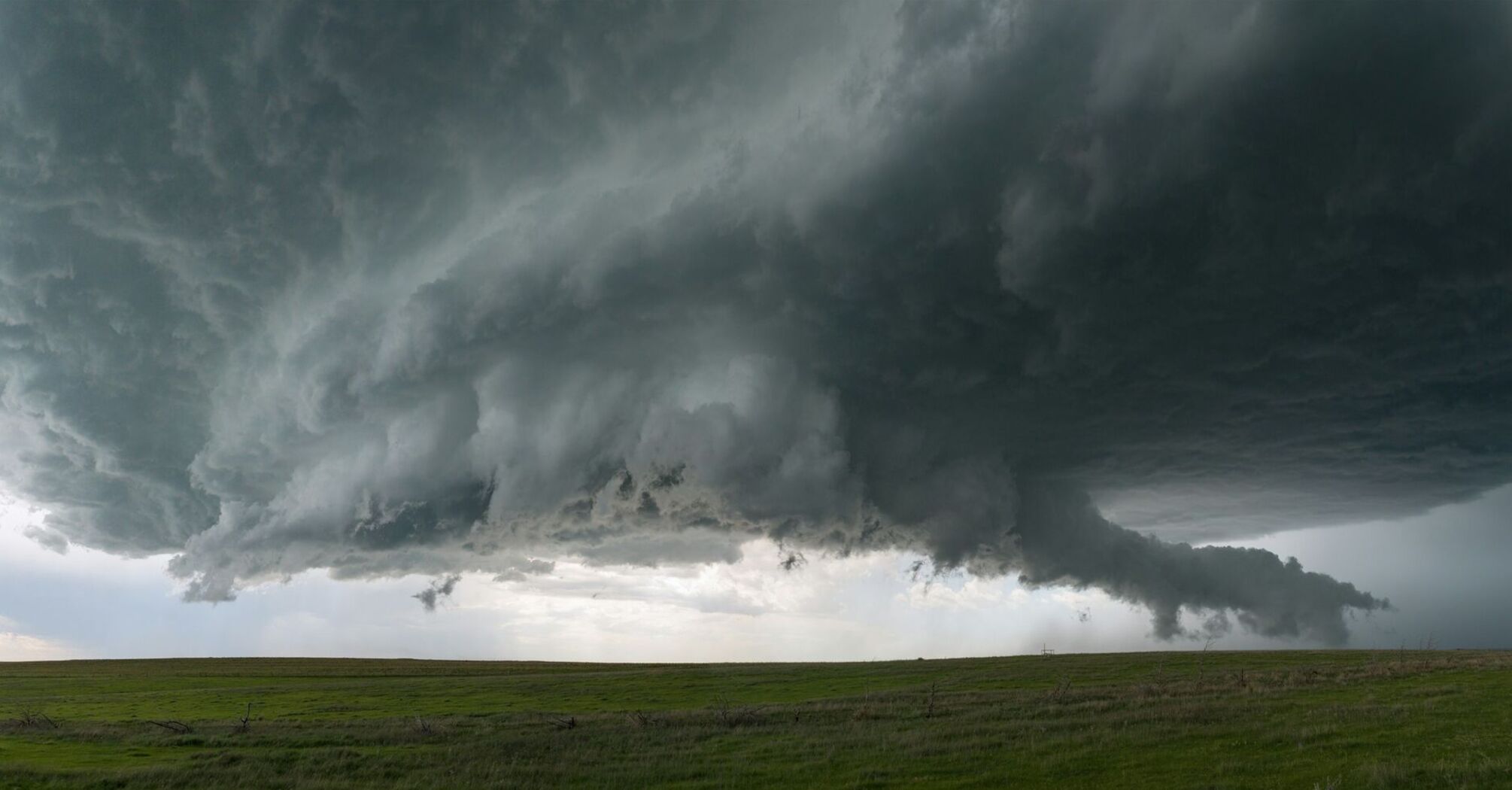 Dark storm clouds hanging over an open grassy field