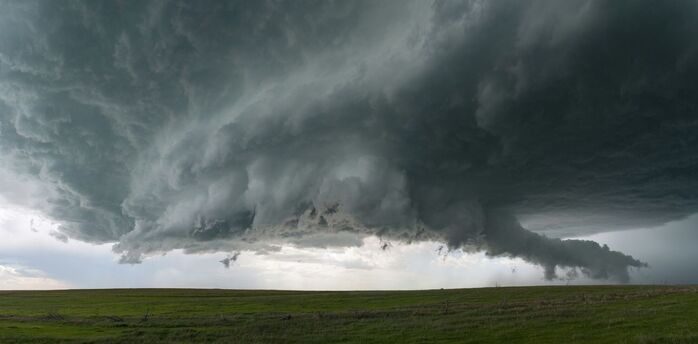 Dark storm clouds hanging over an open grassy field