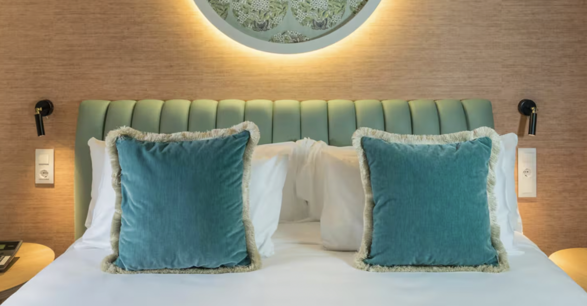 Casa Verbena Madrid bed with turquoise cushions and a decorative wall panel