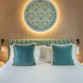 Casa Verbena Madrid bed with turquoise cushions and a decorative wall panel