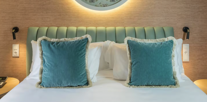 Casa Verbena Madrid bed with turquoise cushions and a decorative wall panel