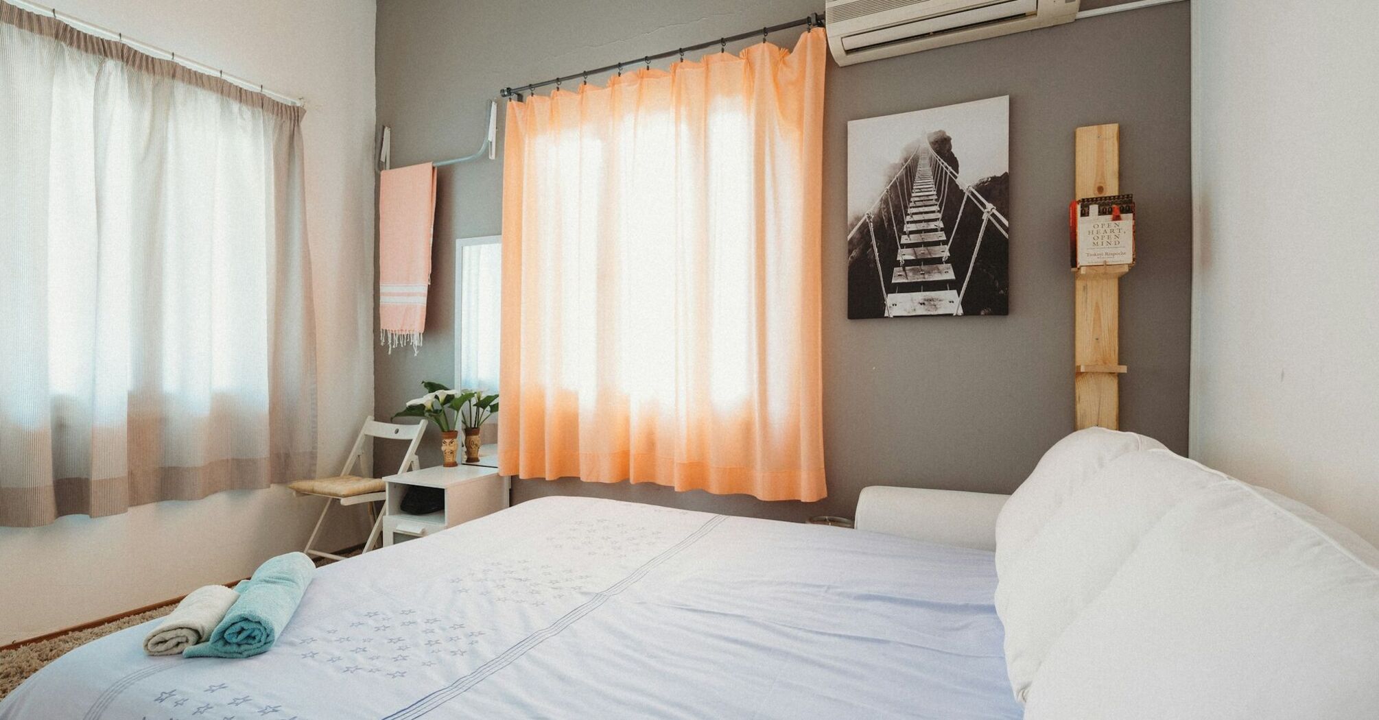 Bright holiday rental bedroom with a made bed and folded towels