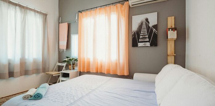 Bright holiday rental bedroom with a made bed and folded towels