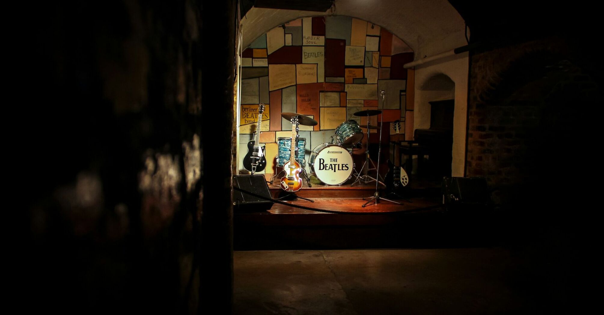 Beatles-themed stage with guitars and a drum kit