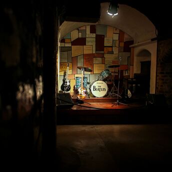 Beatles-themed stage with guitars and a drum kit