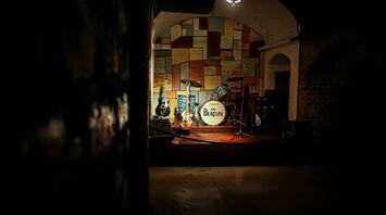 Beatles-themed stage with guitars and a drum kit
