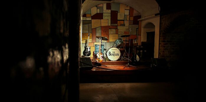 Beatles-themed stage with guitars and a drum kit