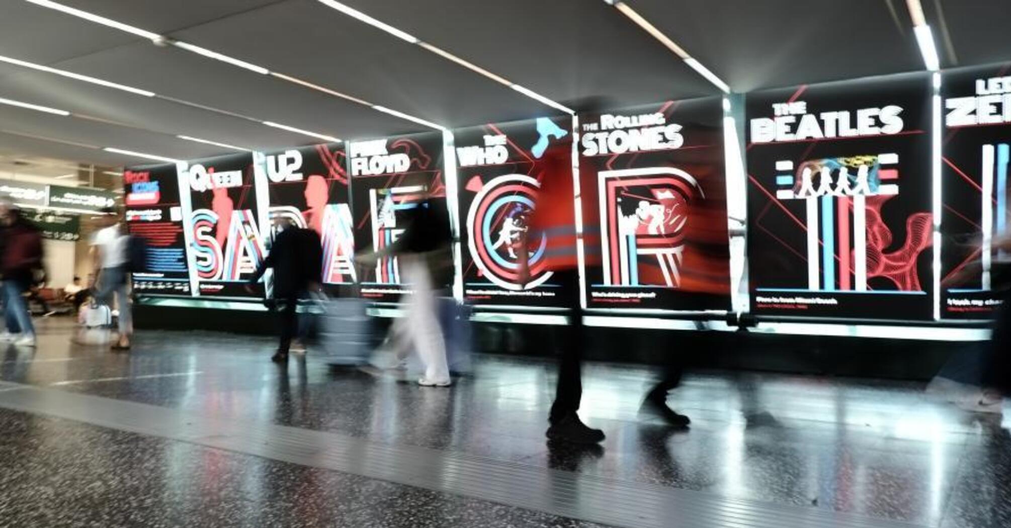 Visitors walking past illuminated Rock Icons displays at Milan Malpensa Airport