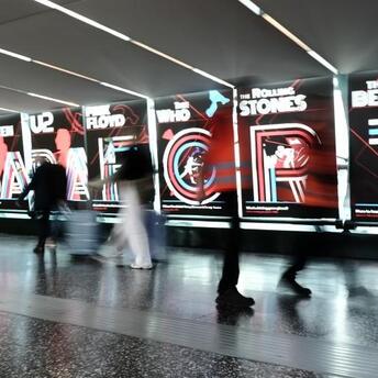 Visitors walking past illuminated Rock Icons displays at Milan Malpensa Airport