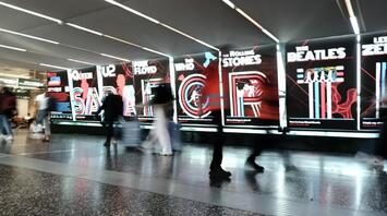 Visitors walking past illuminated Rock Icons displays at Milan Malpensa Airport