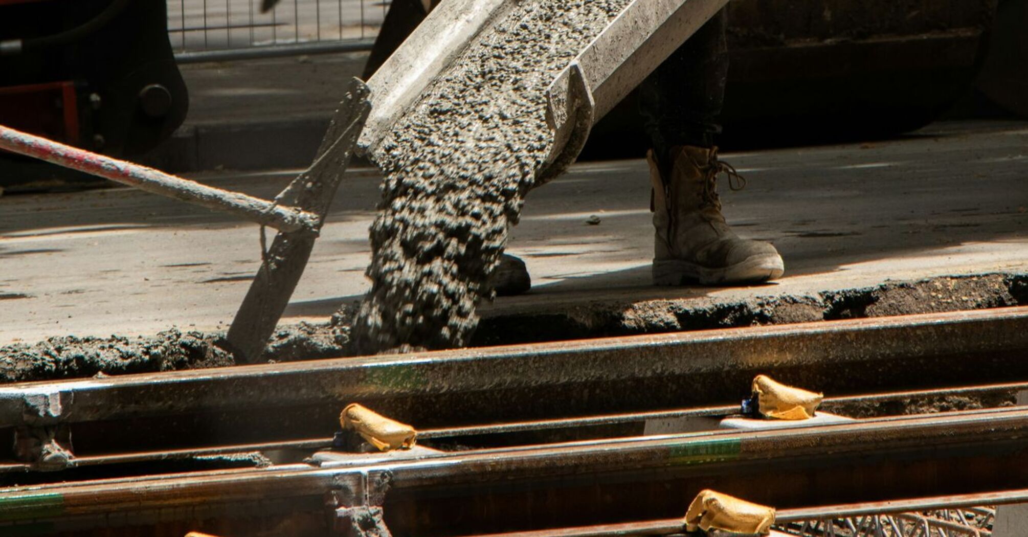 Construction worker pouring concrete beside railway tracks