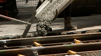 Construction worker pouring concrete beside railway tracks