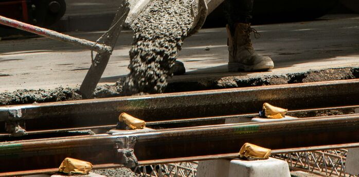 Construction worker pouring concrete beside railway tracks