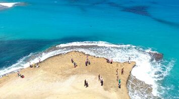 People standing on a rocky outcrop surrounded by turquoise sea