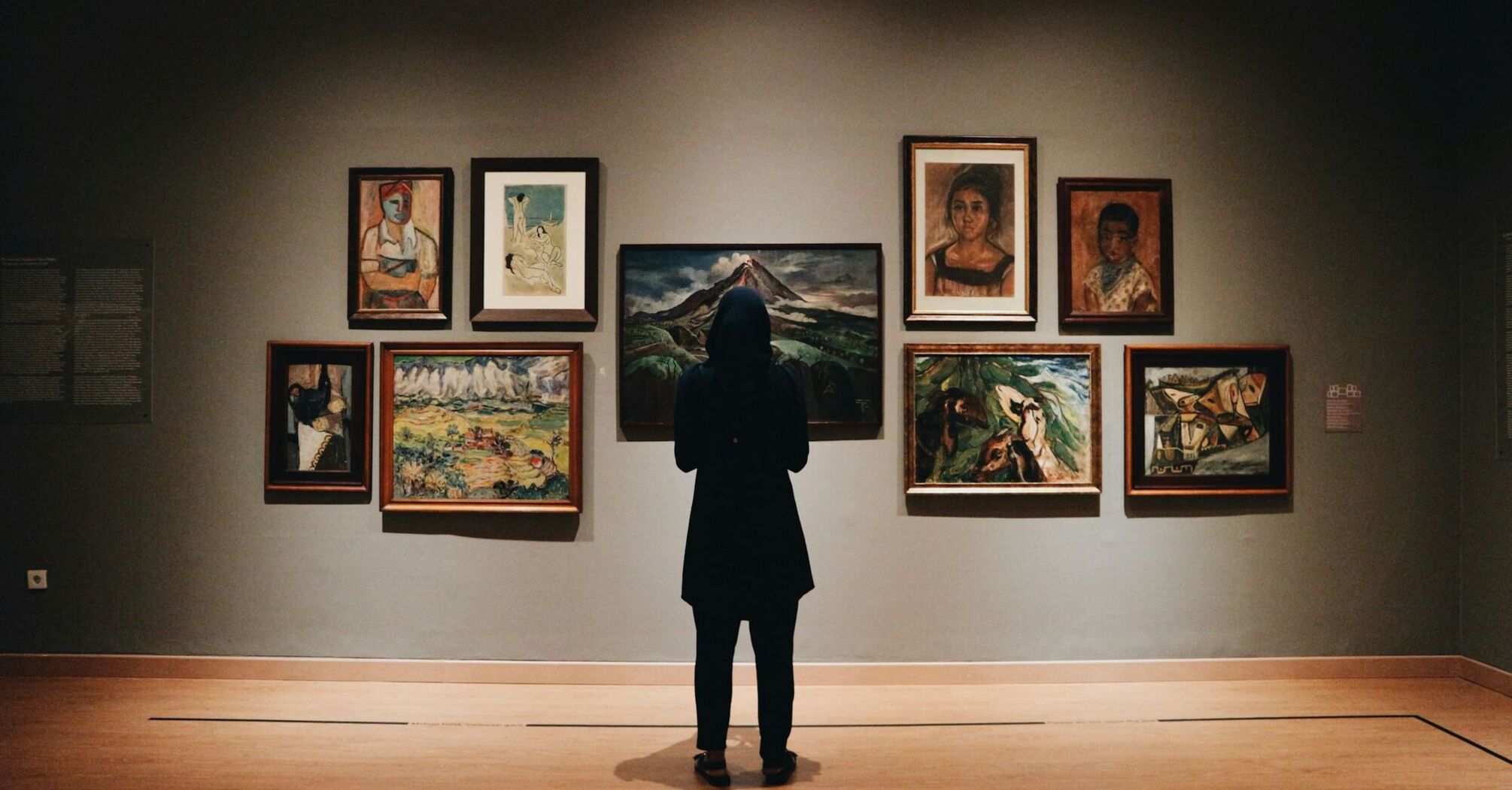 Visitor viewing framed paintings in an art gallery