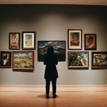 Visitor viewing framed paintings in an art gallery