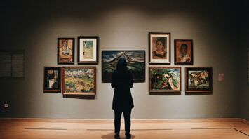 Visitor viewing framed paintings in an art gallery
