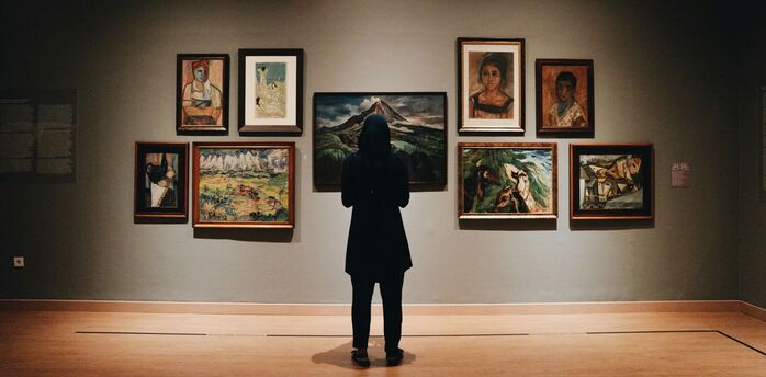 Visitor viewing framed paintings in an art gallery