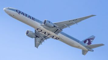 Qatar Airways passenger aircraft flying against a clear blue sky, viewed from below