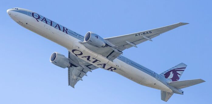 Qatar Airways passenger aircraft flying against a clear blue sky, viewed from below