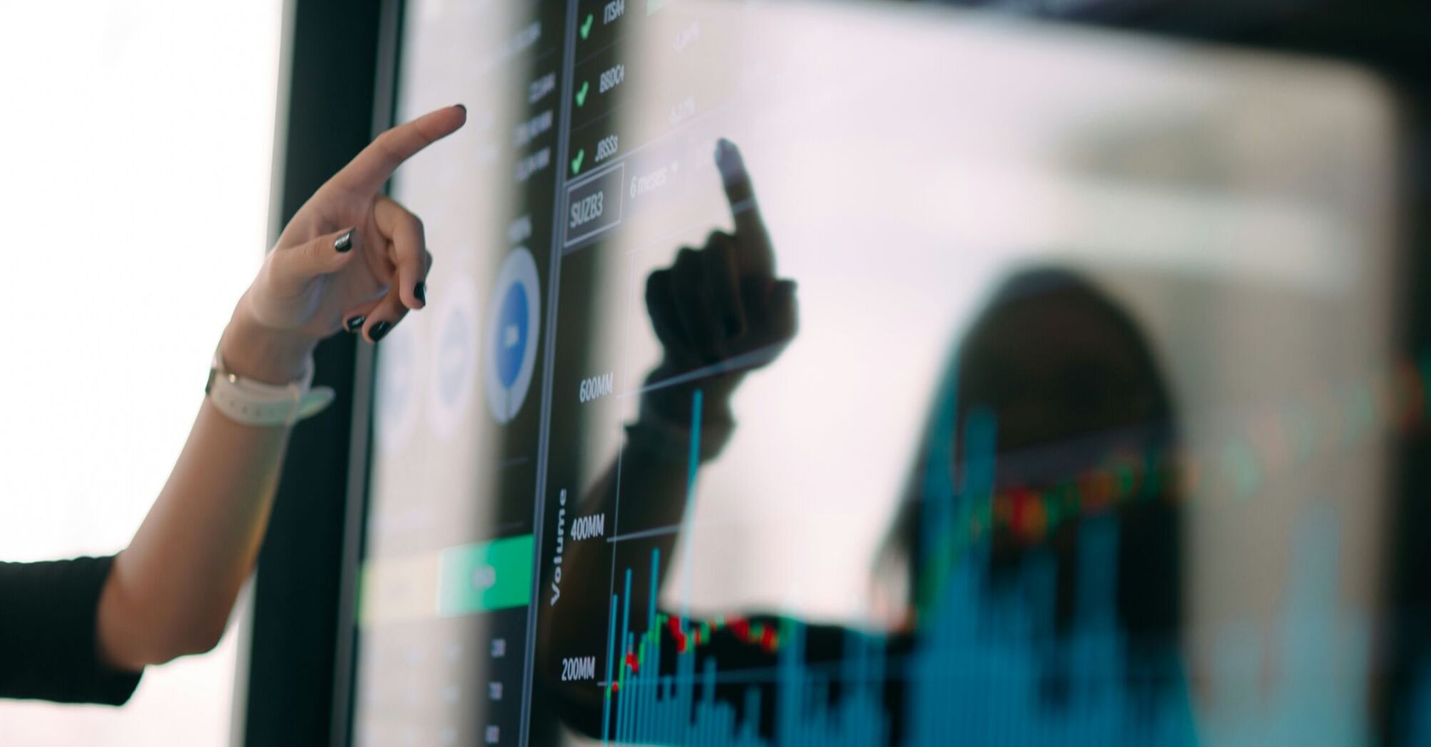 Person pointing at a digital screen displaying charts and data visualizations
