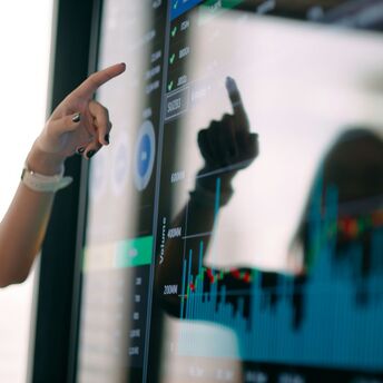 Person pointing at a digital screen displaying charts and data visualizations