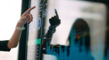 Person pointing at a digital screen displaying charts and data visualizations